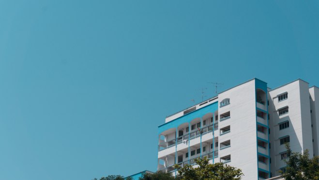White concrete HDB building under a blue sky in the daytime