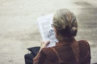 Woman in brown top reading paper