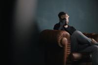 Man sitting on sofa against wall