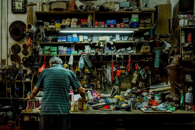 Elderly man facing a shelf of tools