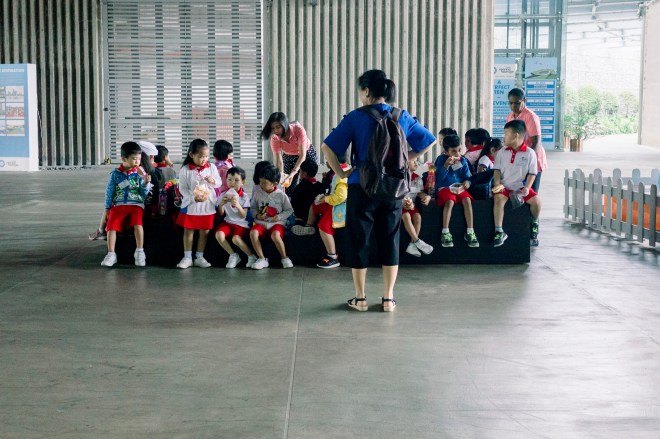 Adult in blue facing a group of preschoolers Lady going down an escalator (Photo by Ng Shi Wen)