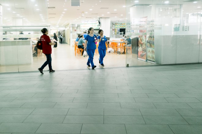 Nurses in blue walking out of a food court (Photo by Ng Shi Wen)